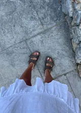 Sandalias marrones con plantilla color suela y doble tira con hebilla metálica.