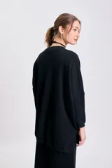 Buzo de punto de corte oversize en color negro, con cuello redondo y mangas largas con puños ajustados.