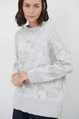 Buzo de tejido de punto con cuello redondo, mangas largas con puños acanalados y diseño estampado de flores en tonos rojos.