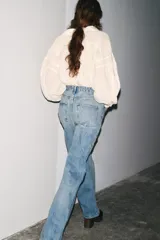 Jeans de tiro alto con corte recto y efecto lavado. Cuenta con cinco bolsillos, trabillas en la cintura y cierre frontal con cremallera y botón.