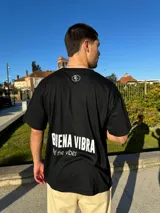 Remera negra de corte semi oversize con estampado en la espalda que dice "BIENA VIBRA feel the vibes" y un logo pequeño en el frente.