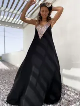 Vestido largo de fiesta color negro, con corte holgado y escote en V profundo decorado con lentejuelas doradas.