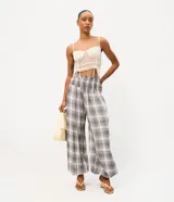 Pantalón de viscosa estilo aladín con estampado a cuadros en tonos grises, blancos y azules. Presenta cintura elástica fruncida y puños ajustados en los tobillos de corte ancho.