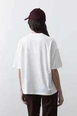 Remera de manga corta con corte boxy fit, color blanco, con estampa frontal geométrica en tonos azul, rosado y marrón.