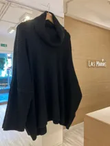 Sweater negro de tejido de punto grueso con cuello alto volcado y corte holgado.