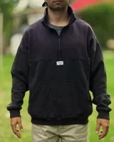 Buzo de corte oversized con medio cierre frontal, confeccionado en una combinación de colores violeta en la parte superior y negro en la parte inferior. Presenta cuello alto, puños y ruedo acanalados, y un bolsillo tipo canguro frontal con etiqueta de la marca.