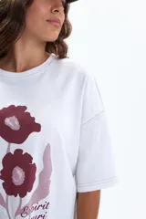 Remera oversize blanca de manga corta, con estampado frontal de flores en tonos bordó y texto "Esprit Fleuri Botanique Marseille, France".
