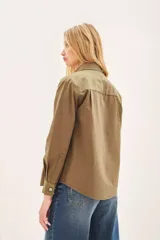 Campera de estilo militar color verde oliva, con corte regular, bolsillos frontales tipo plaqué y cierre frontal con botones metálicos.
