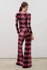 Pantalón de corte recto y tiro alto, confeccionado en tela sublimada con estampado abstracto en tonos rojos, rosas y negros.