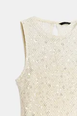 Vestido midi de cuello redondo y sin mangas, confeccionado en tejido de red con lentejuelas brillantes. Presenta un diseño con forro interior corto, aberturas laterales en el bajo y cierre de botón en la espalda.