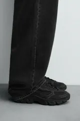 Zapatillas grises con cordones, suela con volumen y diseño irregular.