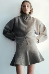 Falda corta de punto con diseño evasé y cintura elástica, confeccionada en tejido texturizado de color gris melange.