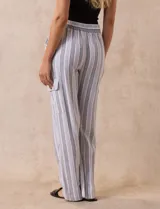 Pantalón cargo de lino a rayas verticales grises y blancas, marca Marissa Olivia. Pretina ancha elastizada con lazo de ajuste, bolsillos inclinados delanteros y bolsillos laterales con botón.