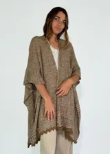 Ruana de tejido de punto color marrón, con diseño abierto y borde de encaje en el dobladillo.