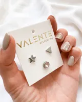 Set de tres pares de aros de acero: un par con forma de estrella, un par con forma de triángulo y un par con forma circular con un cristal engarzado.