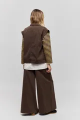 Chaleco de jean negro, de calce relajado con hombros caídos, cuello camisero, cierre frontal con botones y grandes bolsillos aplicados.