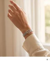 Pulsera de malla metálica plateada con dije central en forma de corazón que contiene la palabra mamá grabada.
