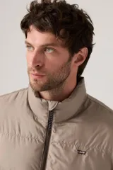 Campera puffer de corte corto y diseño acolchado horizontal, color beige. Cuenta con cierre frontal completo y logo de la marca en el pecho.