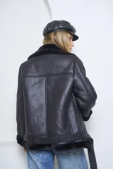 Campera tipo gamulán de cuero sintético negro con interior de corderito sintético al tono. Presenta cierre frontal diagonal, cuello amplio con solapas, bolsillos laterales con cierre y detalles de corderito en puños y ruedo.