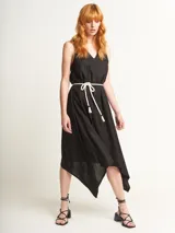 Vestido negro con escote en V y corte irregular con picos en los costados. Incluye lazo de algodón a tono para ajustar en la cintura.