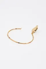 Pulsera rígida de metal dorado con dije central en forma de corazón esmaltado en negro y rodeado de letras de colores. Presenta pequeños detalles esmaltados de colores a lo largo del aro.