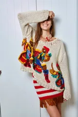 Sweater de lana tejido a mano color crudo, con apliques bordados en relieve de figuras de candombe en colores vibrantes como rojo, azul, amarillo y verde.