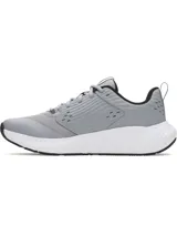 Championes de entrenamiento Under Armour modelo Charged Commit TR 4, color gris con detalles en blanco y negro. Presentan una parte superior de malla transpirable con refuerzos laterales texturizados y el logo de la marca en el costado. Cuentan con mediasuela Charged Cushioning para amortiguación y suela de goma con ranuras de flexión.