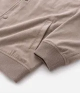 Campera bomber masculina de terciopelo cotelé color beige, con cuello redondo, mangas largas, cierre frontal de botones forrados, bolsillos laterales y terminaciones de elástico en puños y cintura.