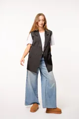 Chaleco largo negro de tela sastrera con doble fila de botones y lazo en la parte trasera.