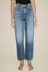Jeans de tiro alto con diseño de cinco bolsillos, trabillas para cinturón y cierre frontal con cremallera y botón metálico.