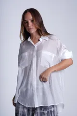 Camisa negra de tela traslúcida con cuello clásico, cierre frontal con botones y dos bolsillos de parche en el pecho.