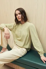 Camisa verde claro de viscosa suave, con cuello mao y botonadura parcial al frente. El detalle de frunces en los hombros y los puños abotonados le suman delicadeza y estilo.