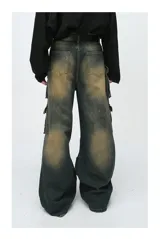 Pantalón de jean ancho (baggy) con lavado oscuro y efecto desgastado en tonos marrones/ocre. Presenta múltiples bolsillos cargo grandes con tapa y botones a presión en las piernas.