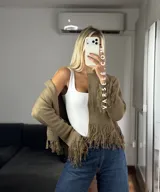 Cárdigan de tejido de punto color crema, con cuello redondo, mangas largas y cierre frontal con botones metálicos. Presenta detalles de flecos en los puños y en el ruedo.