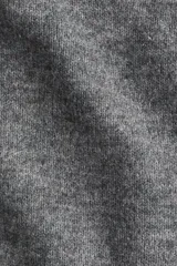 Buzo de punto suave en color gris, con cuello tipo polo, mangas raglán y terminaciones acanaladas en puños y bajo.