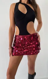 Mini falda de tiro bajo confeccionada en tela recubierta de lentejuelas circulares grandes en color rojo cereza.