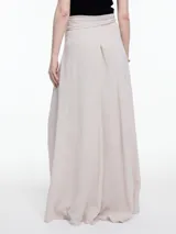Falda larga color beige, de corte evasé y tiro alto, con lazo ajustable en la cintura.