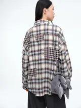 Sobrecamisa de corte oversize con diseño patchwork de cuadros en tonos beige, marrón y negro. Presenta efecto desgastado, cierre frontal con botones y bolsillo en el pecho.