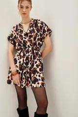 Vestido corto de escote cruzado en V, con mangas cortas tipo kimono y cintura elástica. Presenta un estampado animal print abstracto en tonos marrones, azul oscuro y crema.