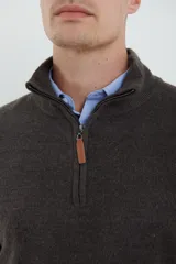 Sweater verde oliva de tejido acrílico con textura similar al cashmere, corte clásico, cuello alto con cierre metálico y tirador de cuerina ecológica.