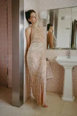Vestido midi de viscosa con estampado floral, cuello halter con abertura frontal y hombros descubiertos. Presenta un detalle de cinturón ajustable con lazada a contraste en la cintura y cierre posterior con botones.