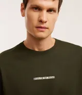 Remera de corte comfort color verde militar, de manga corta, con cuello redondo y estampado frontal pequeño con la leyenda "Speed on the rocks".