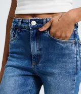Pantalón de jean azul con corte recto y tiro alto. Presenta un acabado con efecto marmorizado, trabillas en la cintura, cierre frontal con botón y bolsillos laterales y traseros.