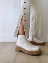 Botas Chelsea de cuero color crudo con elástico lateral, suela track color caramelo y tirador trasero de cuero con textura croco color marrón.