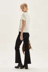 Remera blanca de algodón con cuello redondo y manga corta. Presenta un estampado bordado central con motivos florales y un animal (posiblemente un conejo o liebre) en tonos lila, morado y marrón.