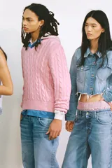 Cazadora crop de denim celeste desgastado, con cuello solapa, manga larga y bajo deshilachado. Presenta parches en forma de corazón en los bolsillos delanteros y detalles de roturas.