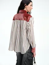 Camisa de corte relajado con estampado de rayas verticales, destacada por detalles en terciopelo en el cuello, puños y canesú. Presenta cierre frontal con botones y mangas largas.