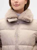 Campera puffer corta de color beige, con cuello de pelo sintético al tono, cierre frontal con cremallera y bolsillos laterales.