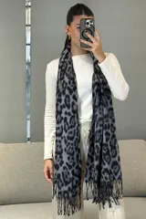 Bufanda rectangular con estampado animal print en tonos blanco y negro, con terminaciones de flecos en los extremos.