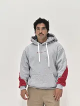 Canguro gris con capucha, de corte holgado, con detalles en color rojo en las mangas y estampado de texto en color rojo en la capucha y el pecho.